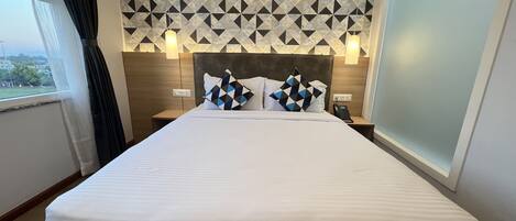 Une chambre d’hôtel avec un lit, deux tables de chevet, un téléphone et une vue sur l’extérieur.