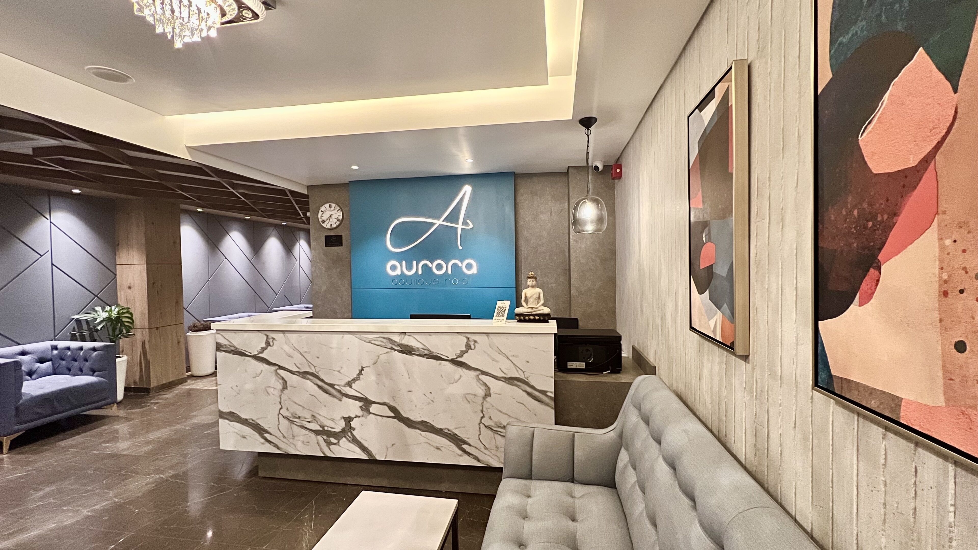 Un comptoir d’accueil moderne avec une enseigne bleue portant l’inscription « Aurora Boutique Hotel ».