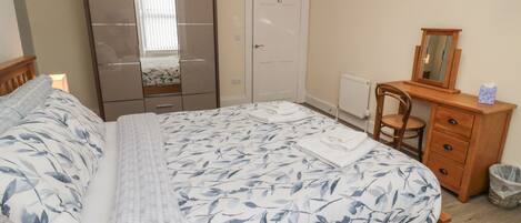 Un dormitorio con cama, armario, cómoda, silla y espejo.