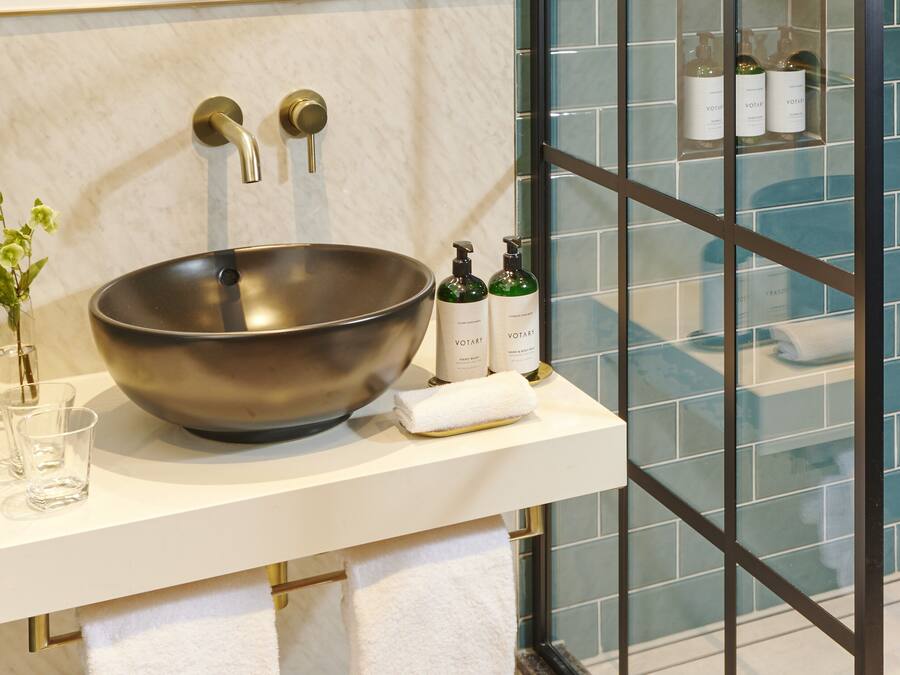 Une salle de bain moderne avec un grand lavabo sur pied, un vase en verre rempli de fleurs et des articles de toilette disposés sur le comptoir.