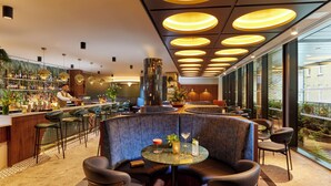 A modern bar area with a bartender, round tables, and a seating area with cushioned booths. - The Chancery Hotel (Dublin)