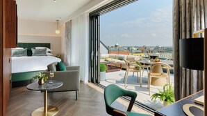 A modern hotel room with a large bed, a sitting area with a table and chairs, and a balcony with a view of the city. - The Chancery Hotel (Dublin)