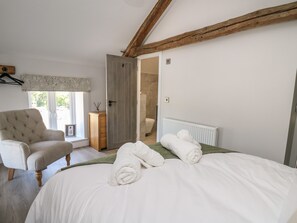 A bedroom with a bed, a chair, a wardrobe, and a bathroom visible through an open door.
