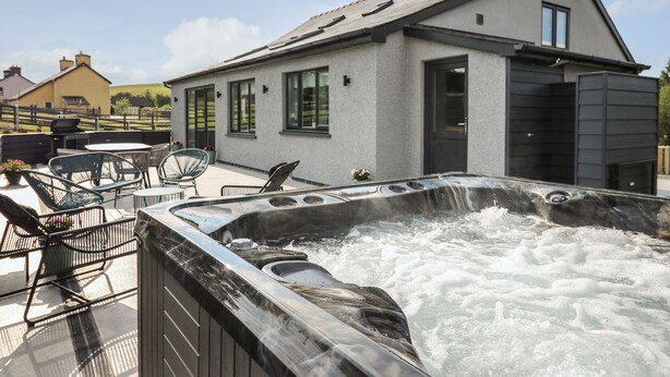 A modern house with a hot tub on the patio.