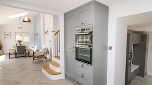 A modern kitchen with a built-in oven and a dining area with a wooden table and chairs.