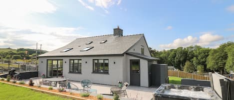 A modern house with a sloped roof, skylights, and a patio area with outdoor furniture.