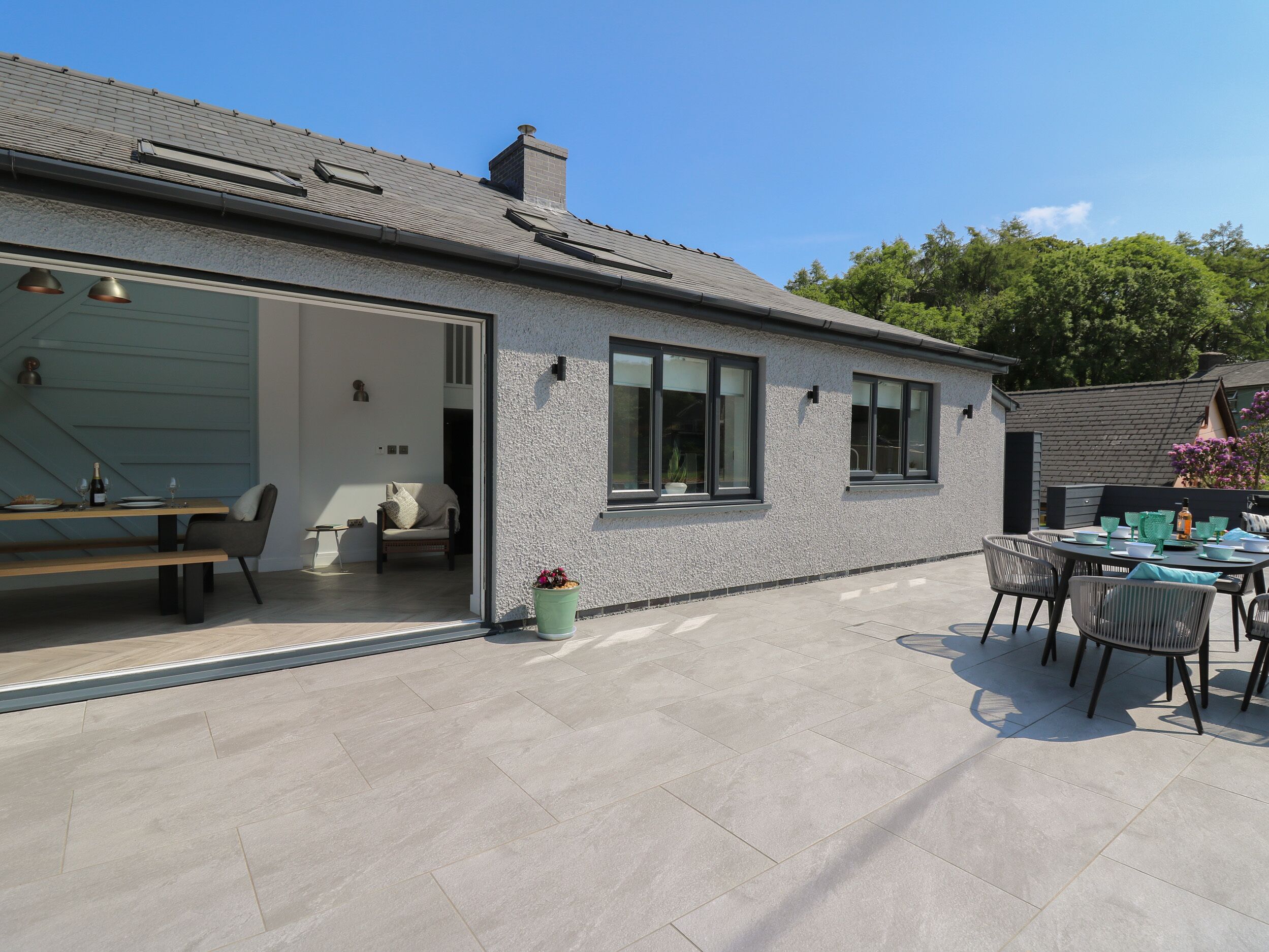 A modern house with a garage, a patio with outdoor furniture, and a small garden area.