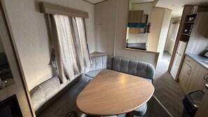 A compact RV interior with a dining table, a built-in bench, and a kitchenette area. - 3-bed Caravan Near Mablethorpe (Louth)