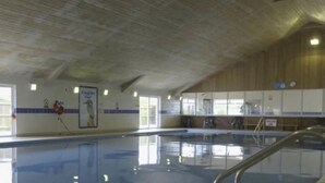 An indoor swimming pool with a tiled floor, a diving board, and a lifeguard stand. - 3-bed Caravan Near Mablethorpe (Louth)