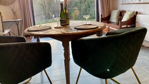 Een eethoek met een ronde tafel, twee stoelen, een wijnfles en een glas op tafel.