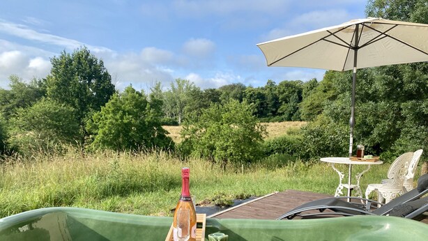 Een groene boot met een fles, een glas en een tafeltje, omgeven door weelderige begroeiing en een heldere lucht.
