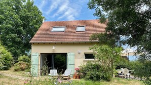 Een huis met een schuin dak, een grote open deur en een klein raam.