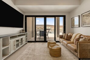 A living room with a sofa, a coffee table, a TV, and a sliding glass door leading to an outdoor patio. - The Copper Rock Oasis: Private Pool + Golf Course Views! (Hurricane)