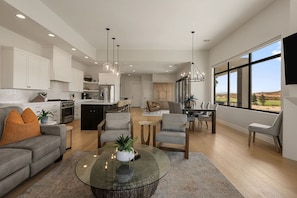 A spacious living area with a modern kitchen, dining space, and a large window offering a view of the outdoors.