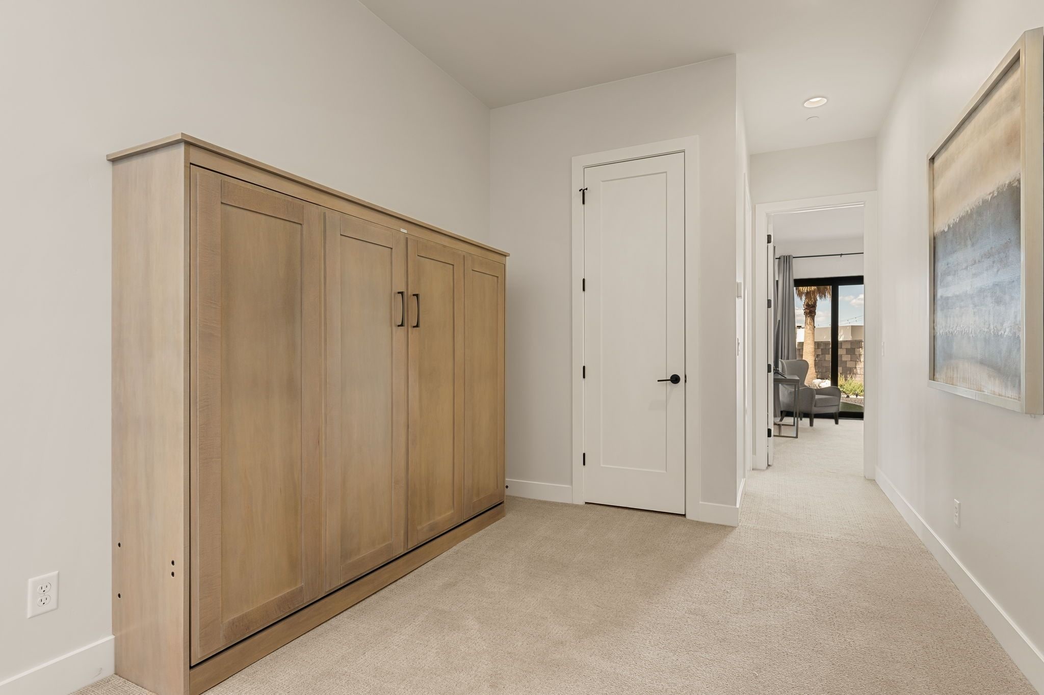 A hallway with a large wooden wardrobe, a white door, and a carpeted floor.