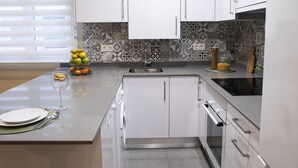 Una cocina moderna con armarios blancos, un salpicadero estampado y un horno empotrado.