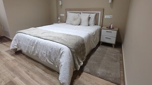 Un dormitorio ordenado con cama, mesitas de noche y una alfombra.