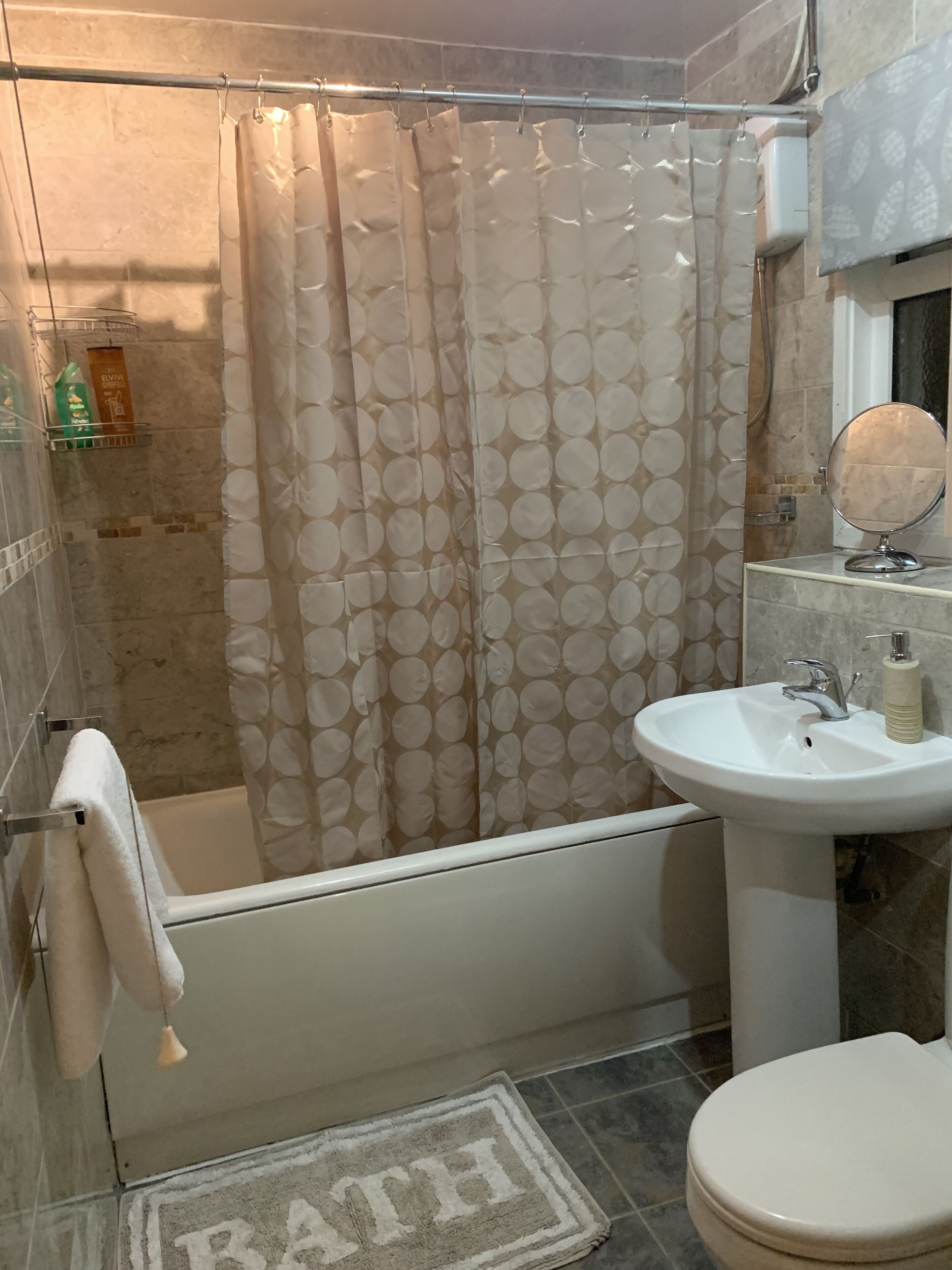 A bathroom with a bathtub, a sink, a toilet, a shower curtain, and a towel rack.