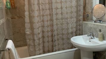 A bathroom with a bathtub, a sink, a toilet, a shower curtain, and a towel rack.