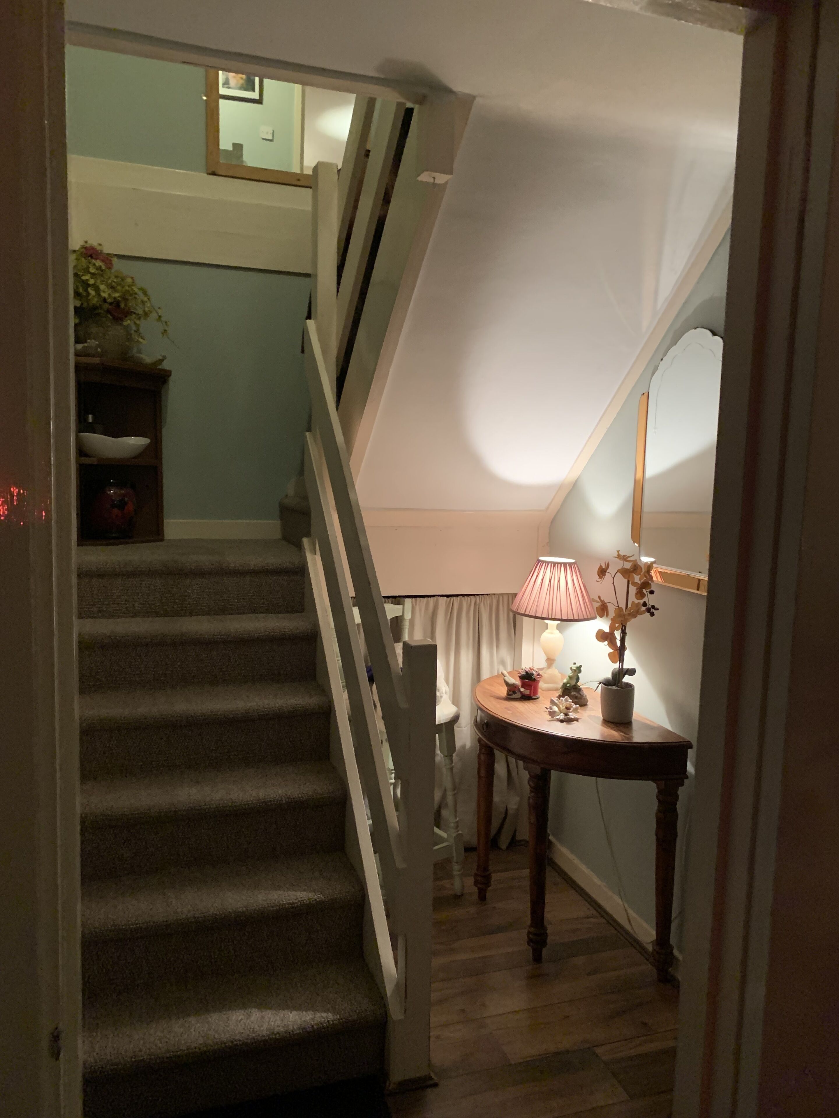 A staircase leading to a landing with a lamp and a small table.