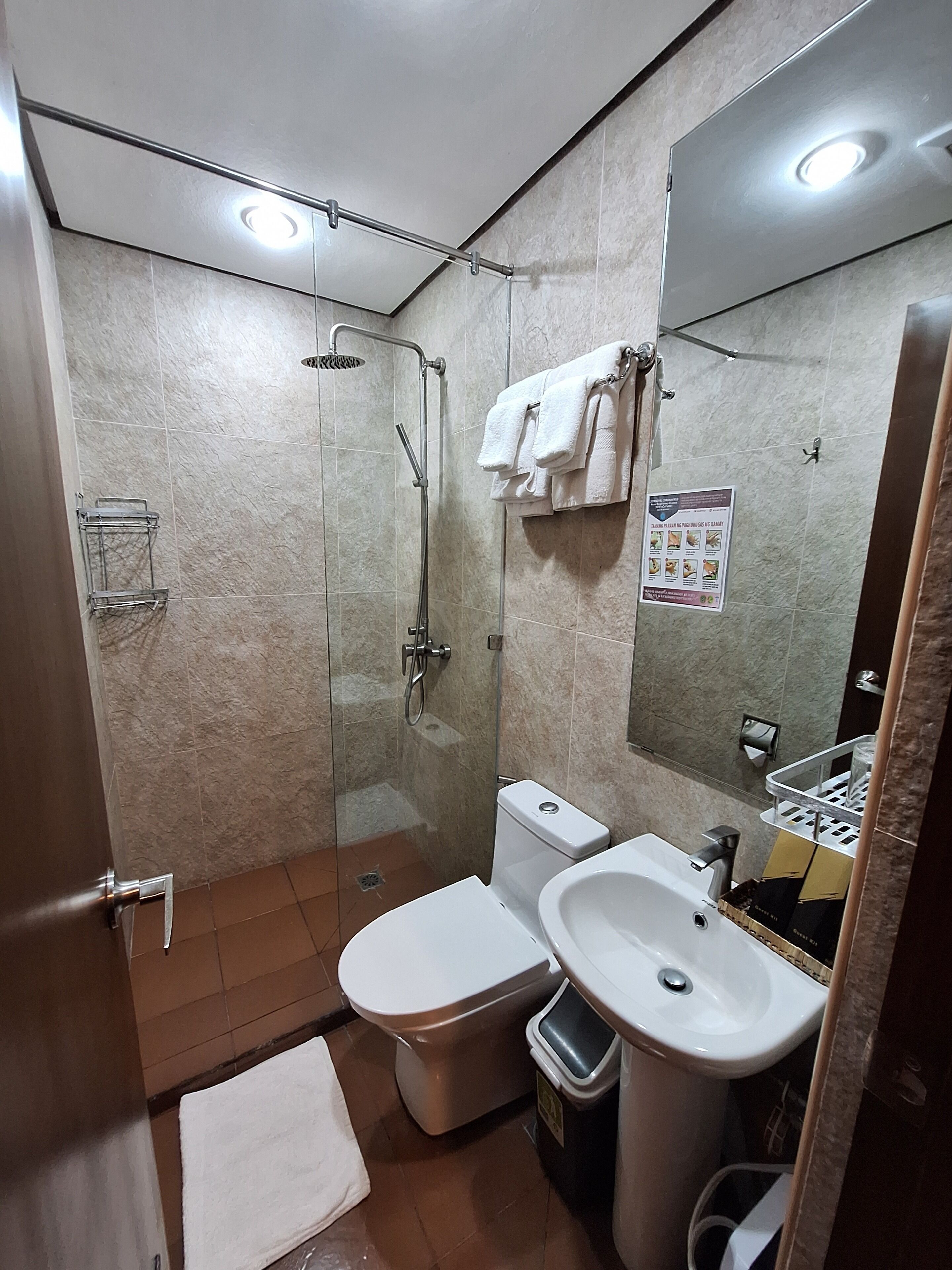 A bathroom with a toilet, sink, shower, and a towel rack.