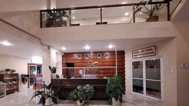 A reception area with a wooden reception desk, multiple clocks, and potted plants.