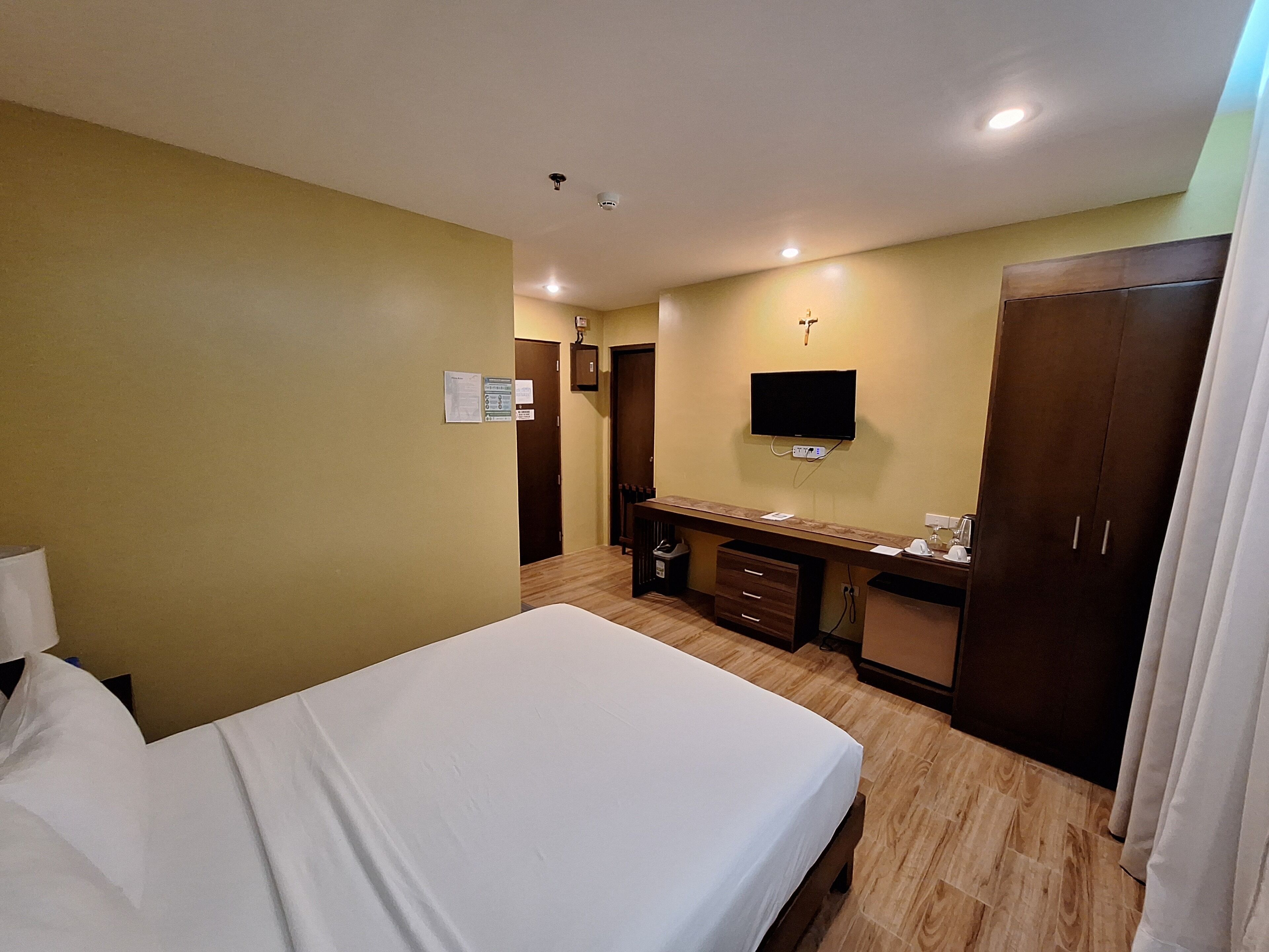 A hotel room with a bed, a desk, a TV, and a wardrobe.