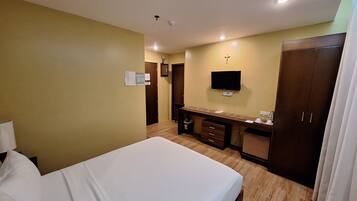 A hotel room with a bed, a desk, a TV, and a wardrobe.
