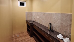 A compact kitchen with a dark countertop, a built-in sink, and a coffee maker.