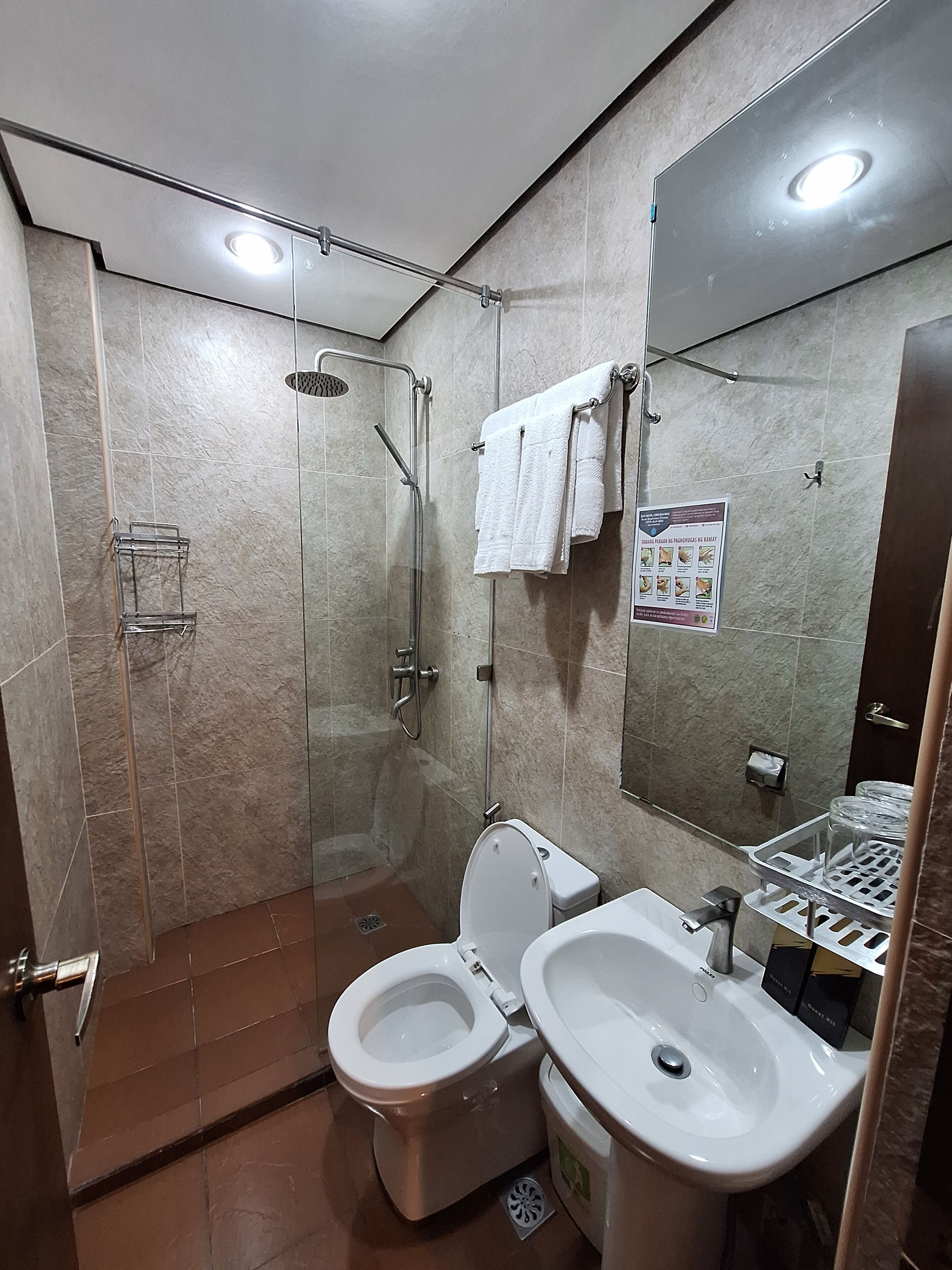 A modern bathroom with a glass-enclosed shower, a toilet, and a sink.