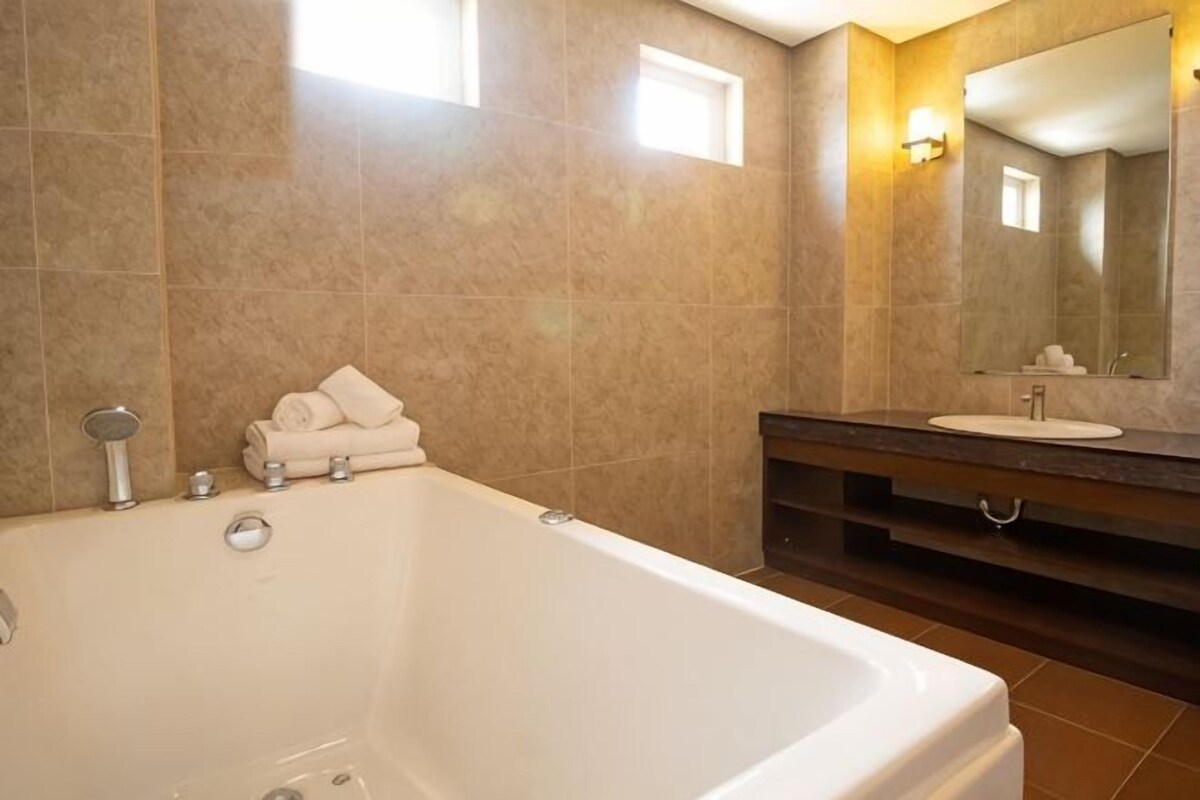 Un bany amb banyera, un lavabo, un mirall i una pila de tovalloles.