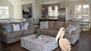 Ein modernes Wohnzimmer mit einer Sofagarnitur, einem Couchtisch und einer Küche im Hintergrund.