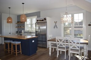 Een moderne keuken met een centraal eiland, witte eetstoelen en hanglampen.
