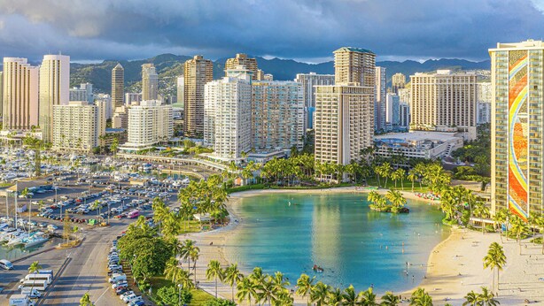 A coastal cityscape with high-rise buildings, a marina, and a beach.
