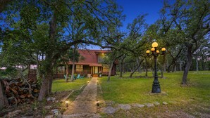 Une maison de campagne rustique, avec un chemin de pierres menant à une terrasse en bois.