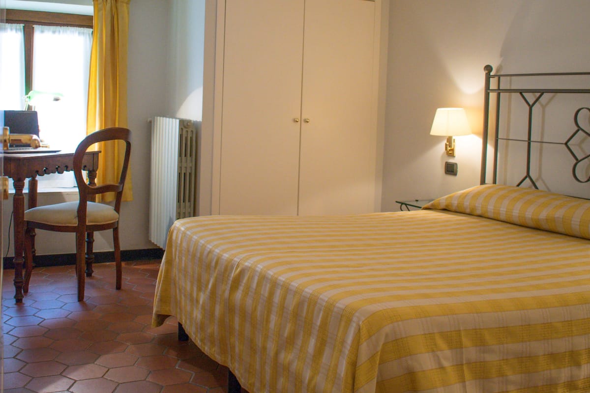Une pièce comprenant un lit, une chaise, un bureau et un radiateur.