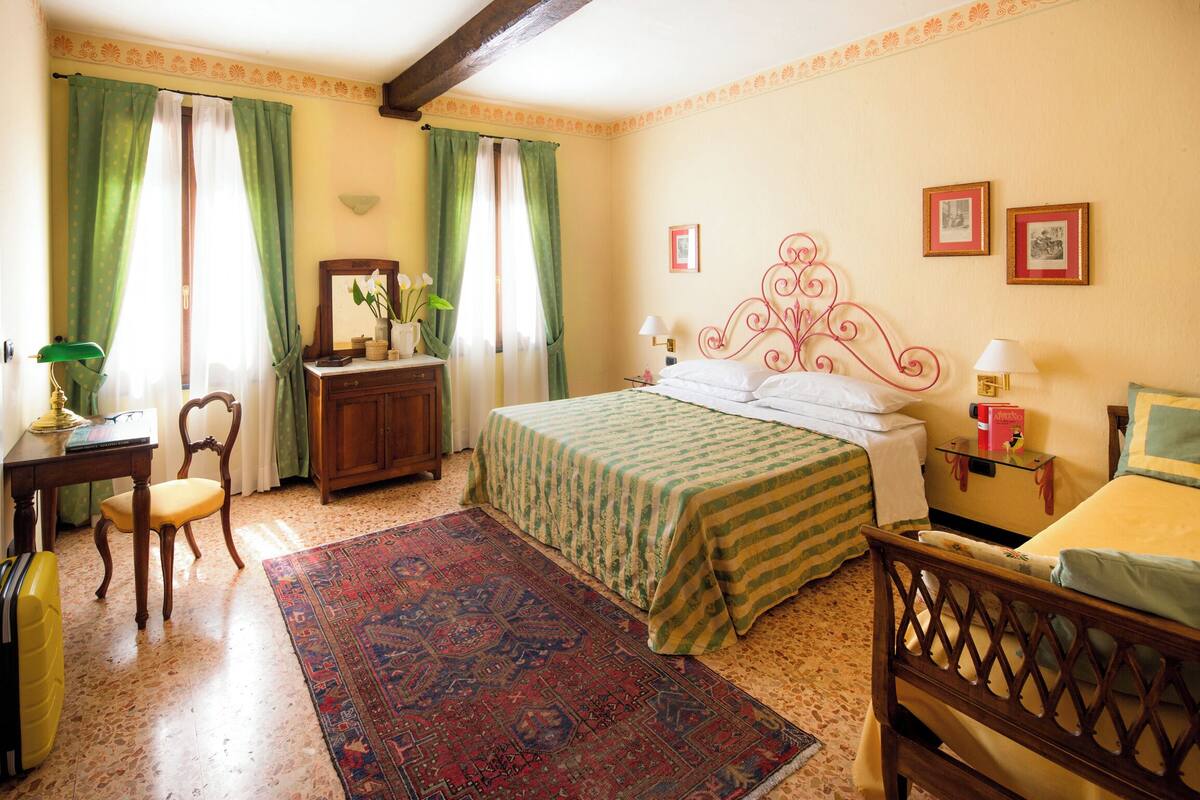 Une chambre à coucher comprenant un lit, un bureau, une chaise, une commode et un tapis.