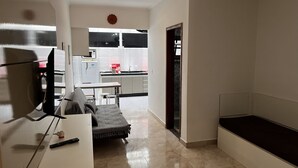 A compact living space with a kitchenette, a dining area, and a small seating area. - Maranduba Ville II (Ubatuba)