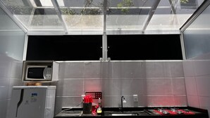 A kitchen with a microwave, sink, and stove, a skylight, and a view of trees. - Maranduba Ville II (Ubatuba)