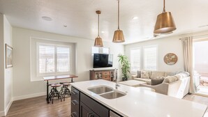 Una cocina moderna con una isla grande, electrodomésticos de acero inoxidable e iluminación colgante.