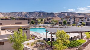 Zona residencial con piscina, mobiliario exterior y montañas al fondo.
