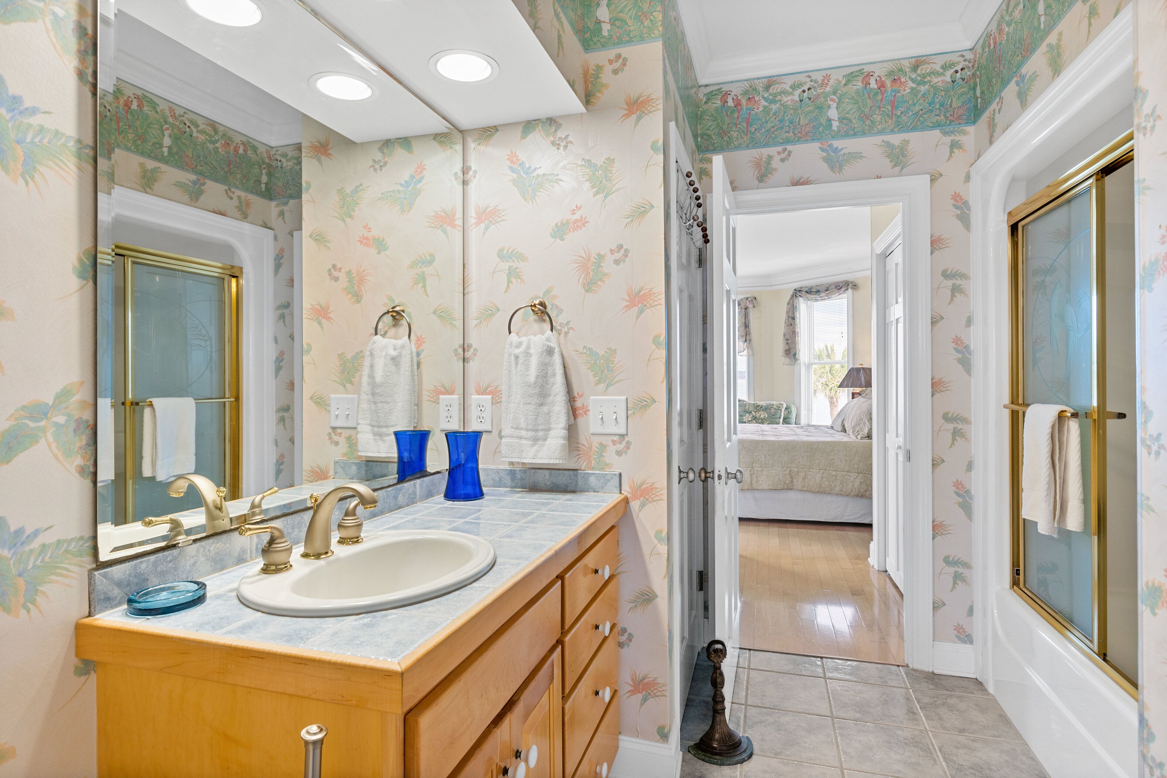Une salle de bain avec un lavabo, un miroir et deux vases bleus posés sur le comptoir.