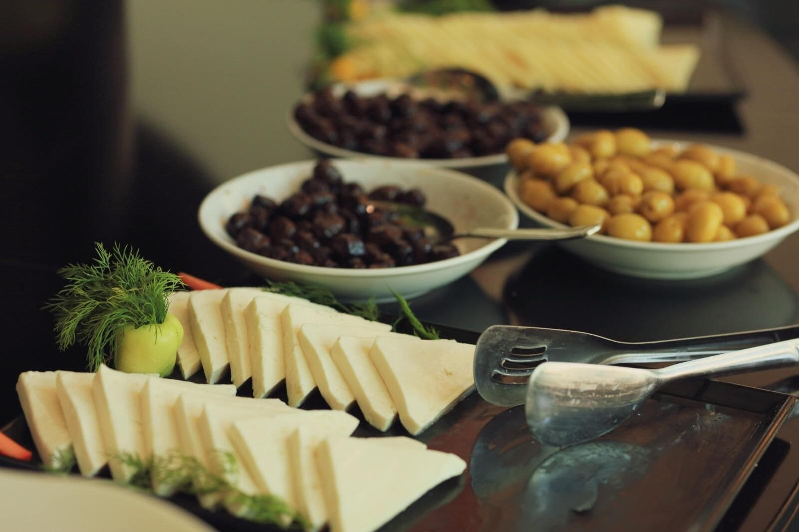 Ein Buffet mit verschiedenen Speisen, darunter Käse, Oliven und Nüsse.