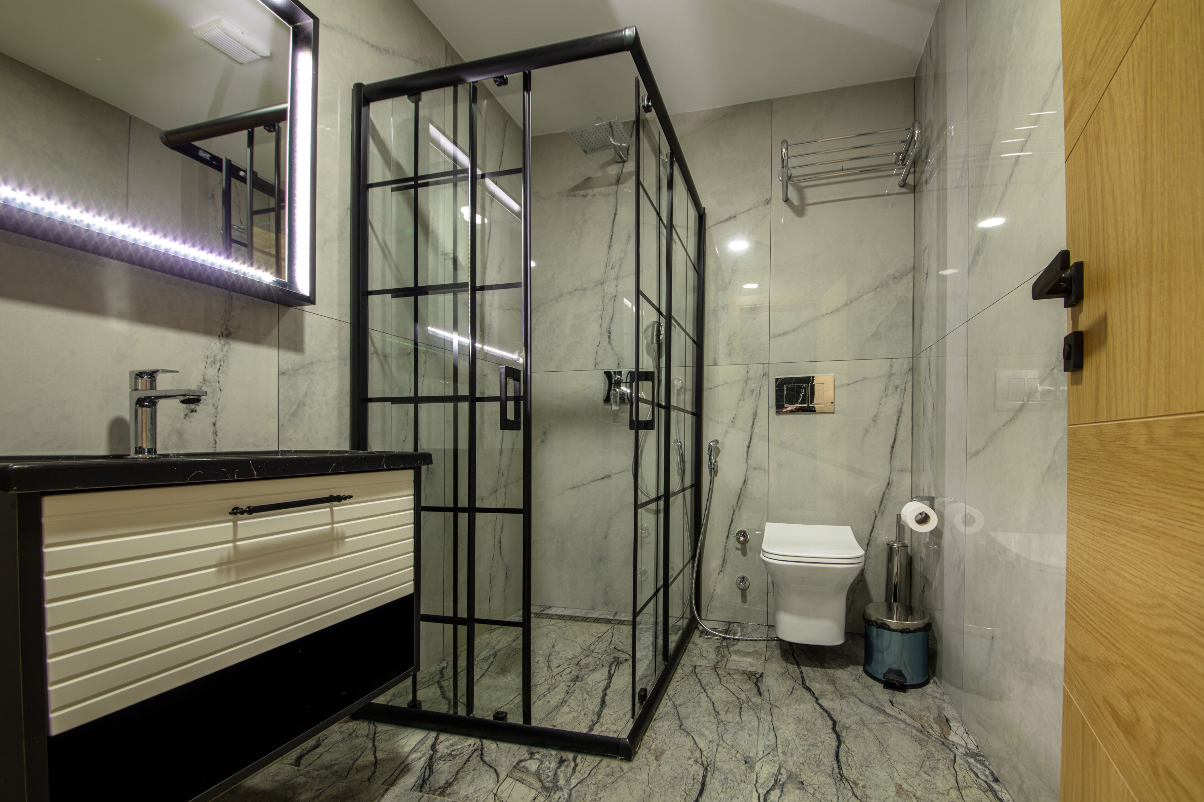 Ein modernes Badezimmer mit Duschkabine aus Glas, einer weißen Toilette und einem Waschtisch mit schwarzer Arbeitsplatte.