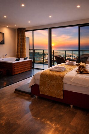 A modern hotel room with a large bed, a bathroom with a bathtub, and a balcony with a sunset view. - Air Barbaros Hotel (Trabzon)