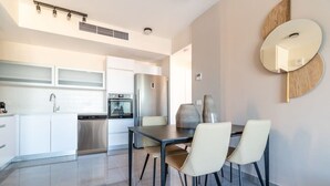 A modern kitchen with white cabinets, a stainless steel refrigerator, and a dining area with a table and chairs. - Jerusalem 1BDR: Old City View By Isrentals (Jerusalem)