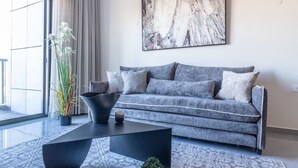 A modern living room with a grey sofa, a black coffee table, and a large abstract painting on the wall. - Jerusalem 1BDR: Old City View By Isrentals (Jerusalem)
