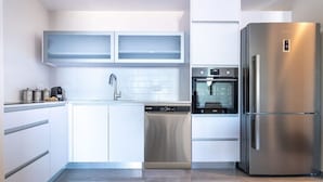 A modern kitchen with white cabinetry, a stainless steel dishwasher, an oven, and a refrigerator. - Jerusalem 1BDR: Old City View By Isrentals (Jerusalem)
