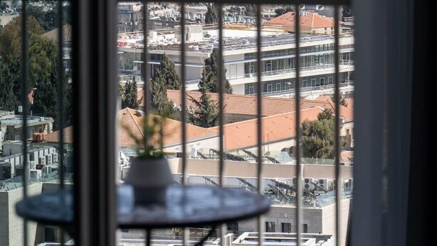 A view through a window with a view of a historical site, including a golden dome, and modern buildings in the foreground. - Jerusalem 1BDR: Old City View By Isrentals (Jerusalem)
