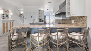 Una cucina moderna con un'isola centrale, sgabelli da bar e mobili bianchi.